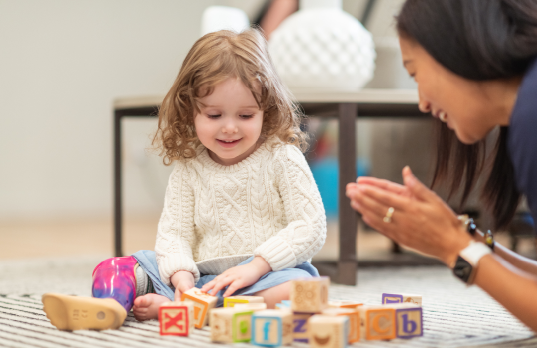 a photo of a girl and Therapist playing with blocks